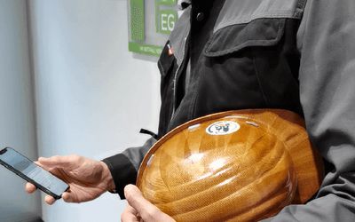 Mann mit Handy und Helm in der Hand