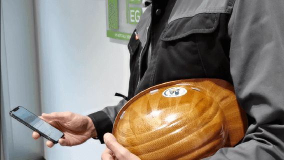 Mann mit Handy und Helm in der Hand