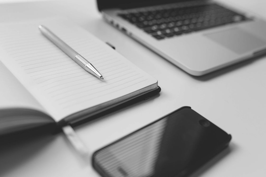 Bild eines Schreibtisches mit Notepad, Handy und Laptop