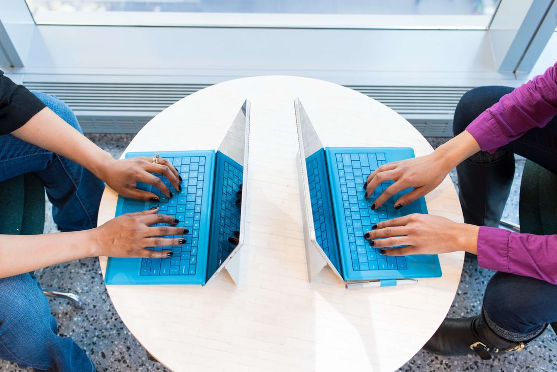 Zwei Personen arbeiten am Laptop gegenüber voneinander