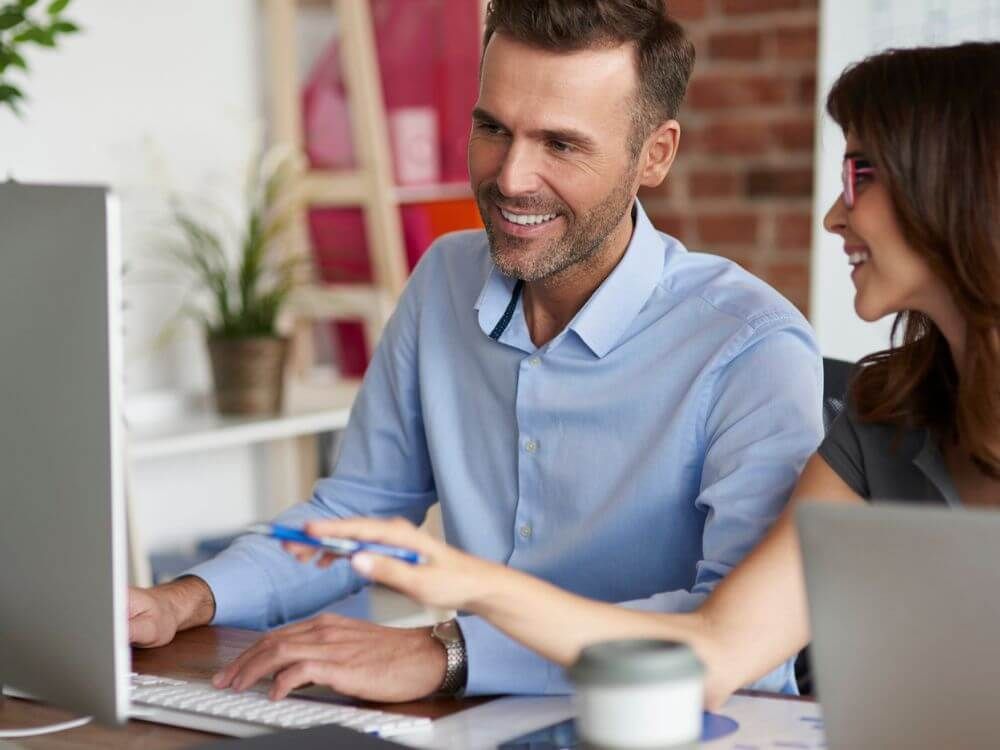 Mann und Frau arbeiten gemeinsam vor Computer Bildschirm