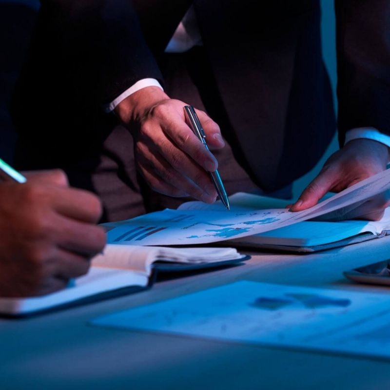 Hand hält Stift über Finanzdokument